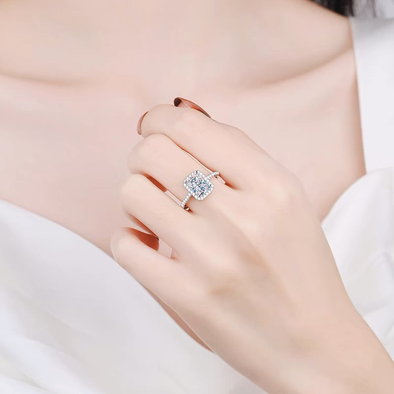 a woman wearing a ring with a cushion cut diamond